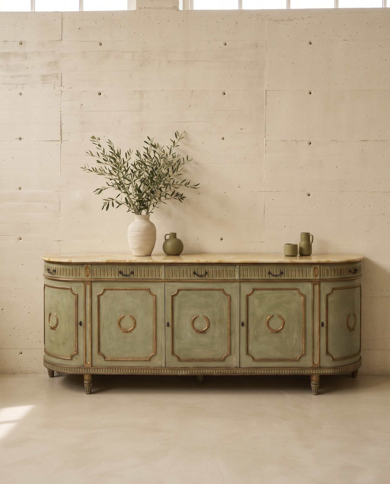 Credenza dipinta in verde salvia con cinque ante decorate da corone d'alloro dorate e piano in marmo giallo, vista di fronte