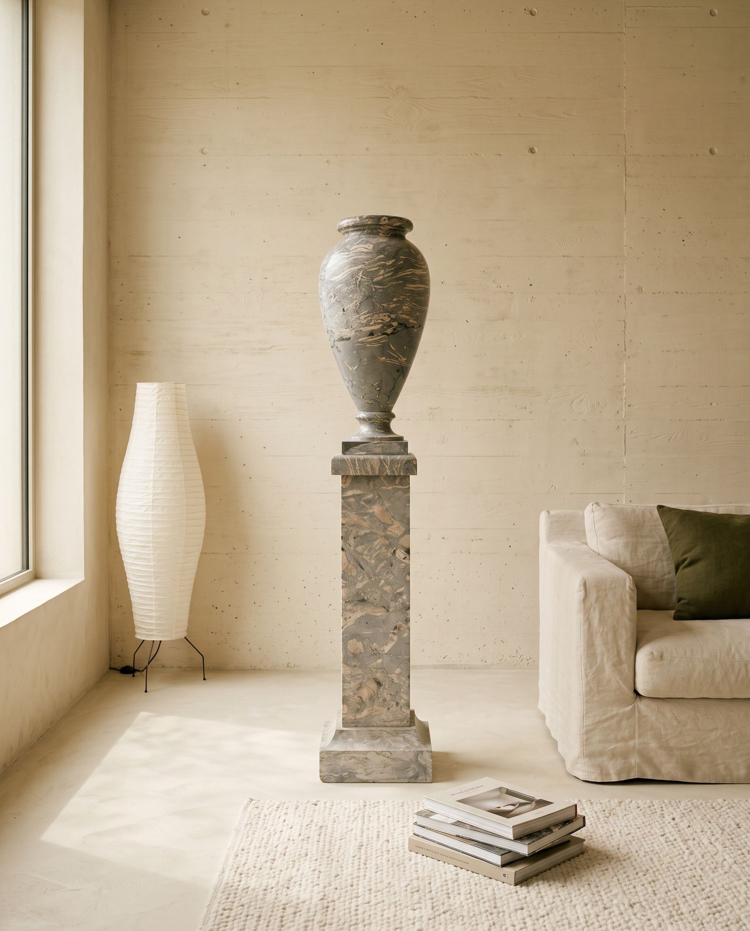 Vaso in marmo grigio sulla sua colonna, visto di fronte in un soggiorno color panna
