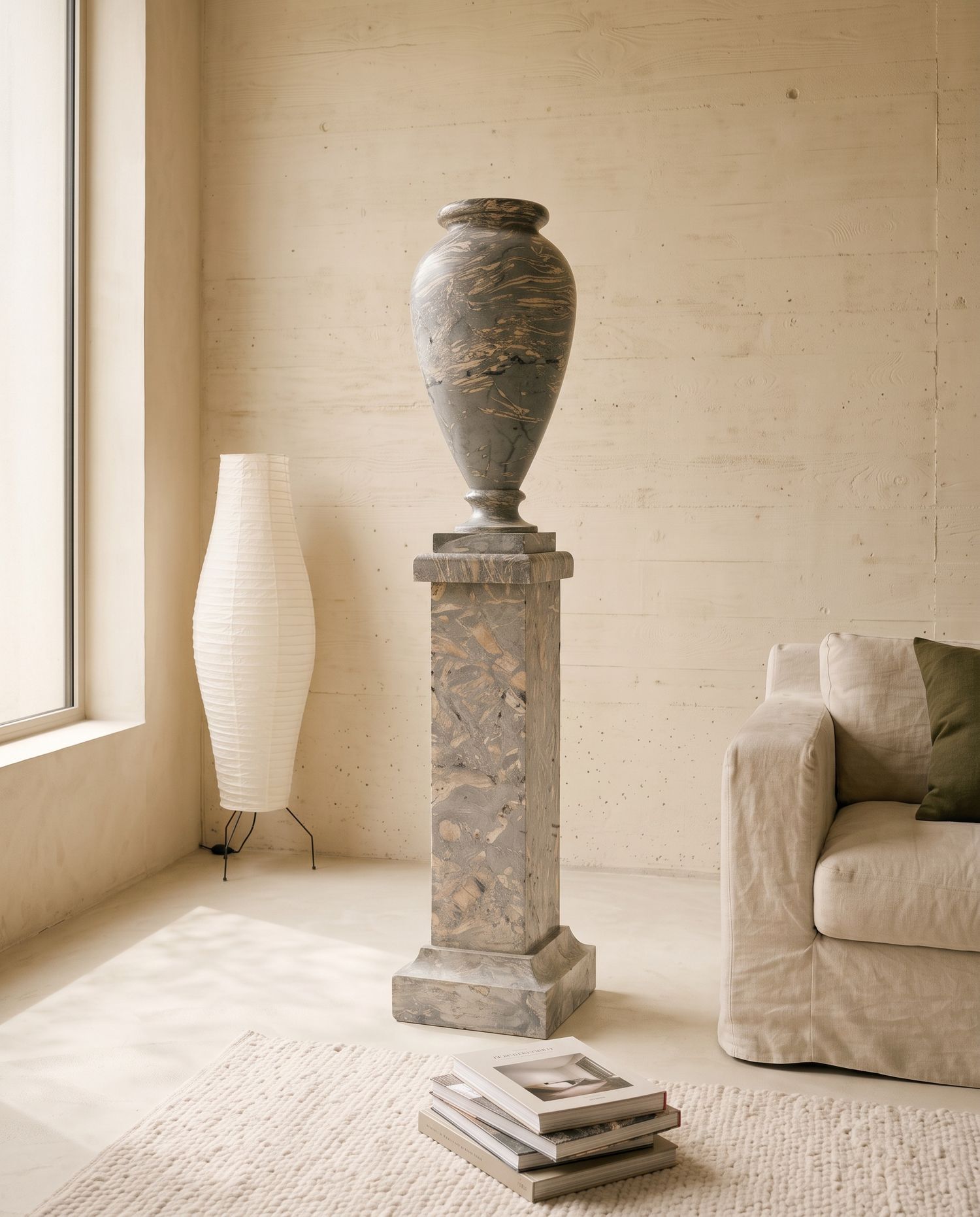 Vaso in marmo grigio con colonna visto di tre quarti, accanto a una lampada di carta